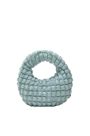 Light blue woven bag with a round handle and a fluffy texture.