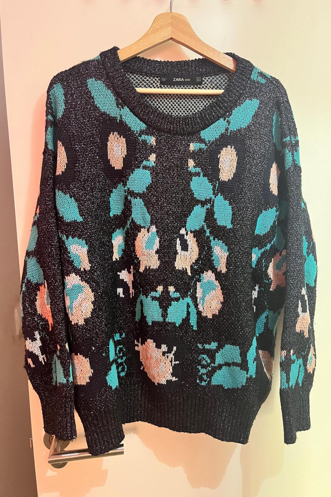Front view of black jumper with floral print in pink and green, round neck and long sleeves.