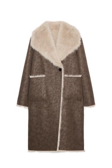 Front view of a brown reversible long coat with a faux fur effect, lapel collar, front pockets, and a double-breasted button fastening.