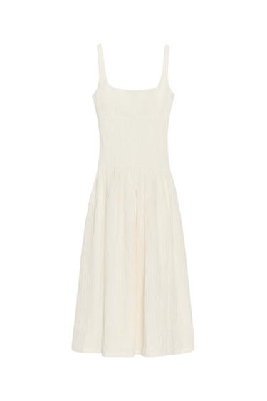 Front view of a cream midi dress with a square neckline, wide straps and texture. Flared hem.