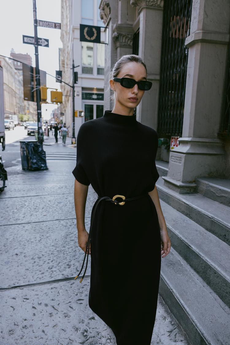 �ern� pleten� �aty s rol�kem, kr�tk�mi ruk�vy a p�skem se zlatou sponou.