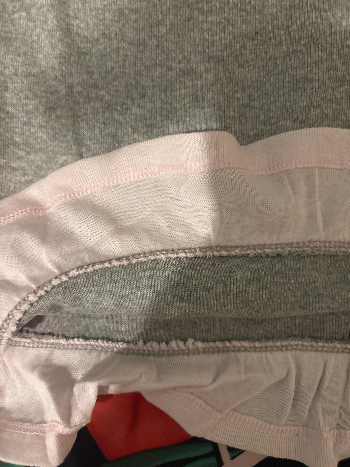 Grey fabric with a white border and visible stitching. Close-up detail of texture and finish. Partially visible background.