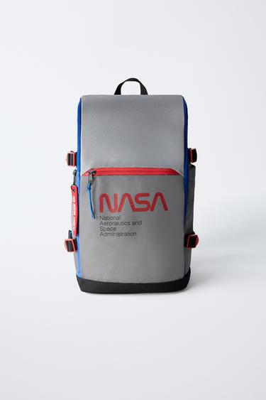 Vorderansicht eines grauen Rucksacks mit dem Text "NASA National Aeronautics and Space Administration" und roter Vordertasche.