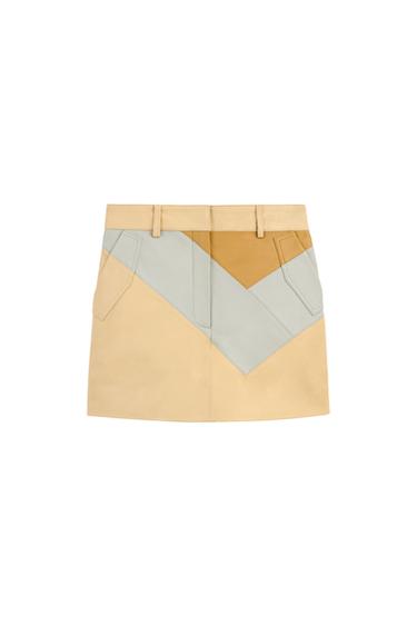 Front view of a short skirt with a geometric design in beige, blue and brown tones, with side pockets.