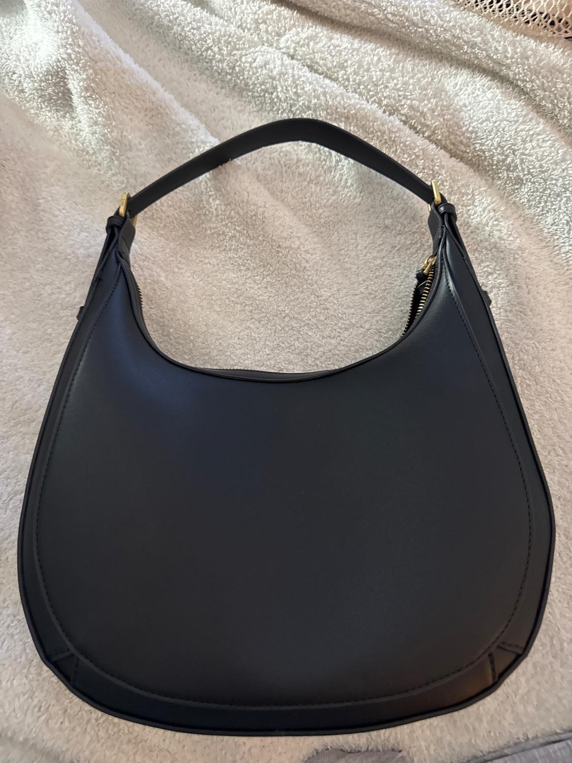 Front view of a black purse with a handle and gold zipper closure.