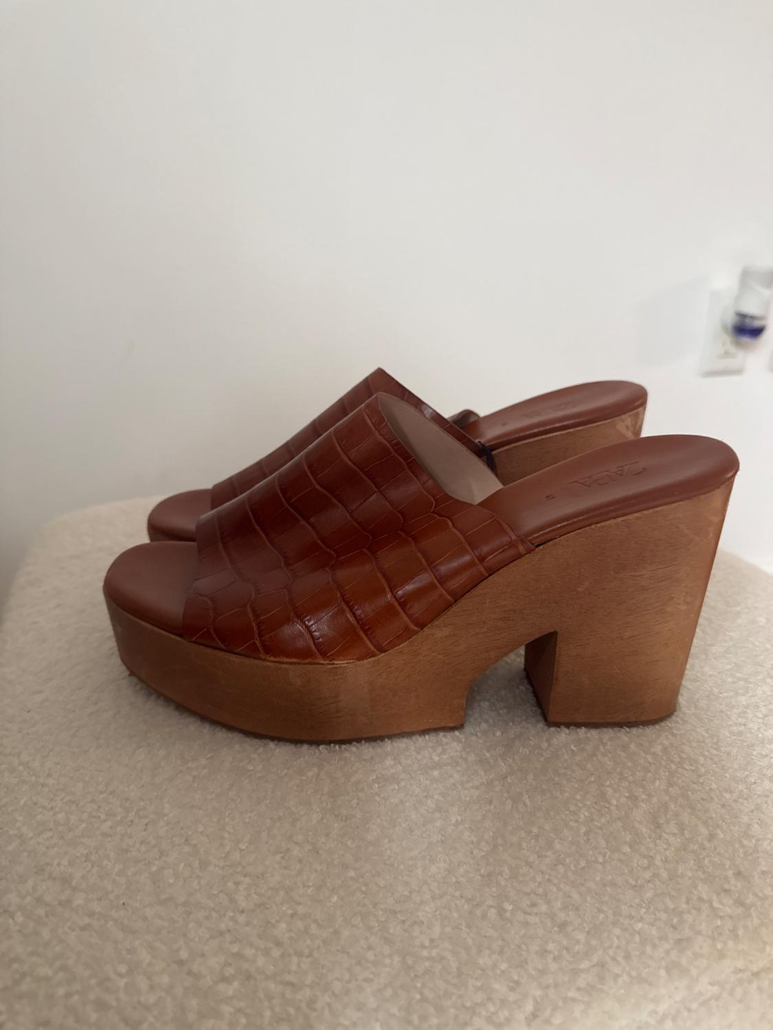 Side view of brown high-heeled sandals with crocodile texture.
