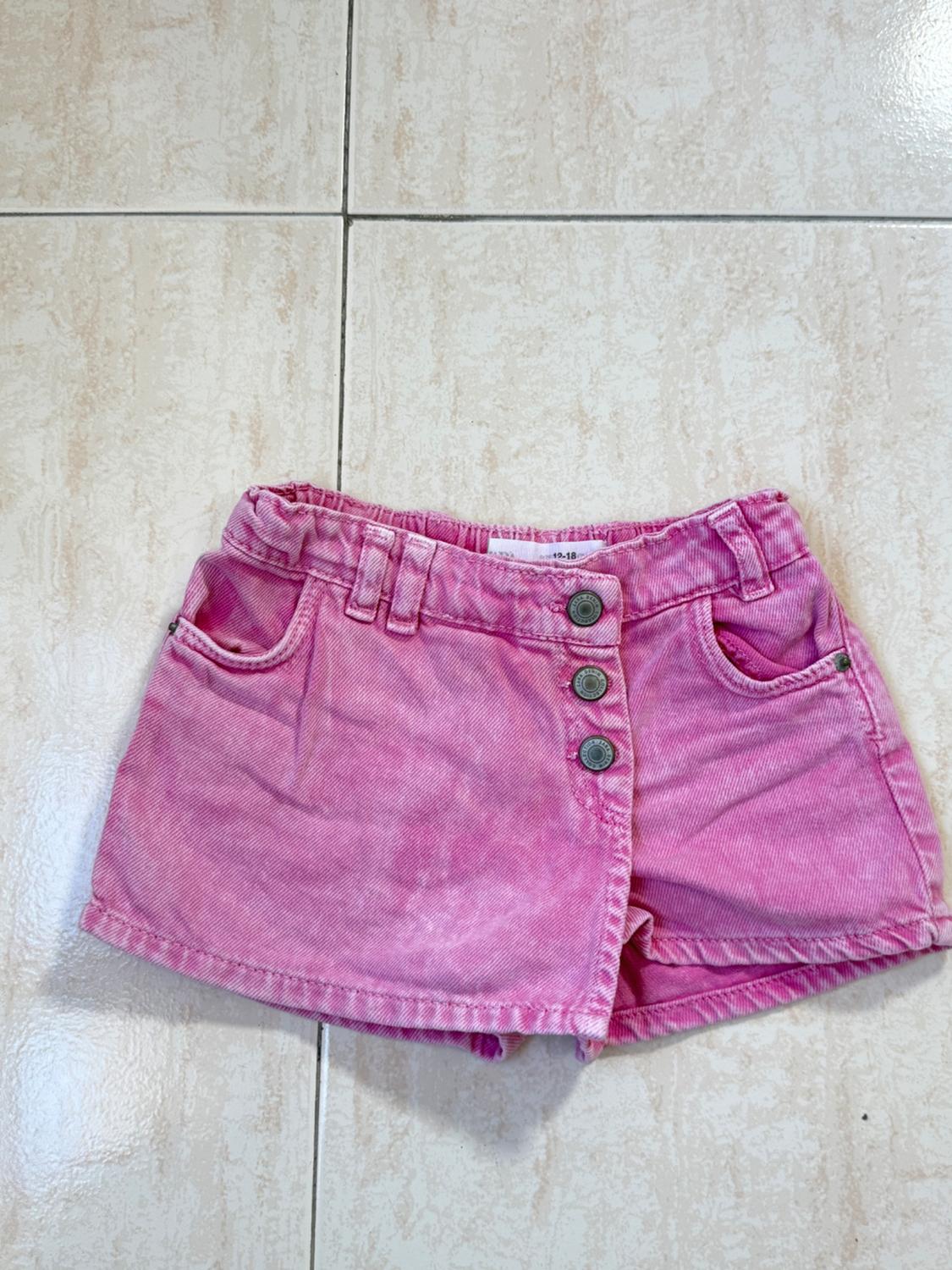 Pink corduroy shorts with front buttons and pockets, on a light tiled floor.