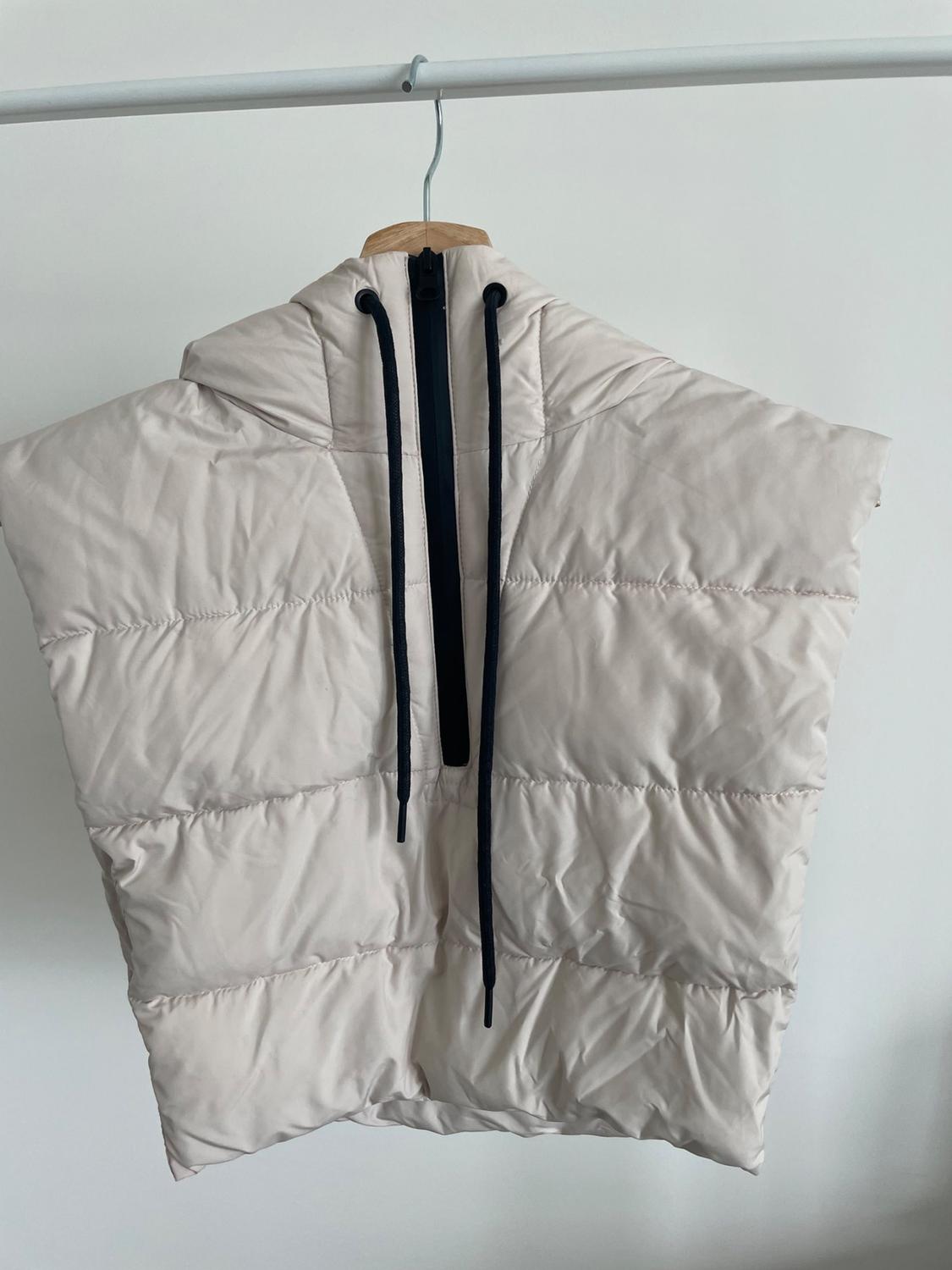 Rear view of beige padded gilet with hood and black zip fastening.