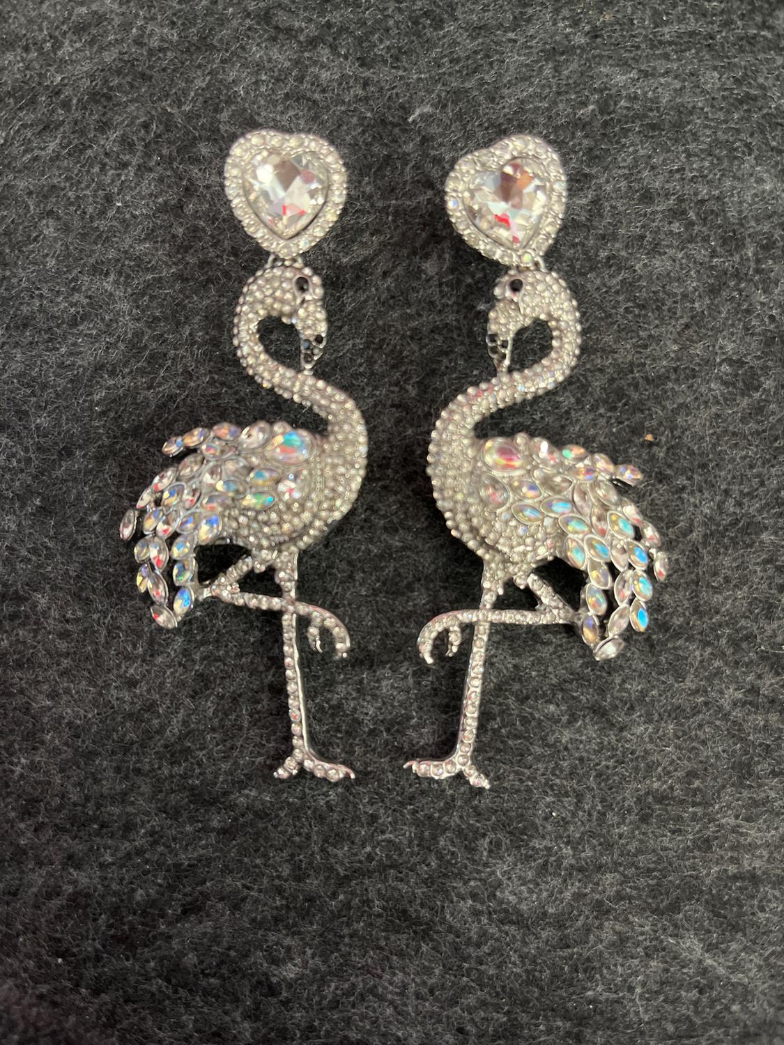 Flamenco earrings with rhinestone inlays and glittering details on a dark grey background.