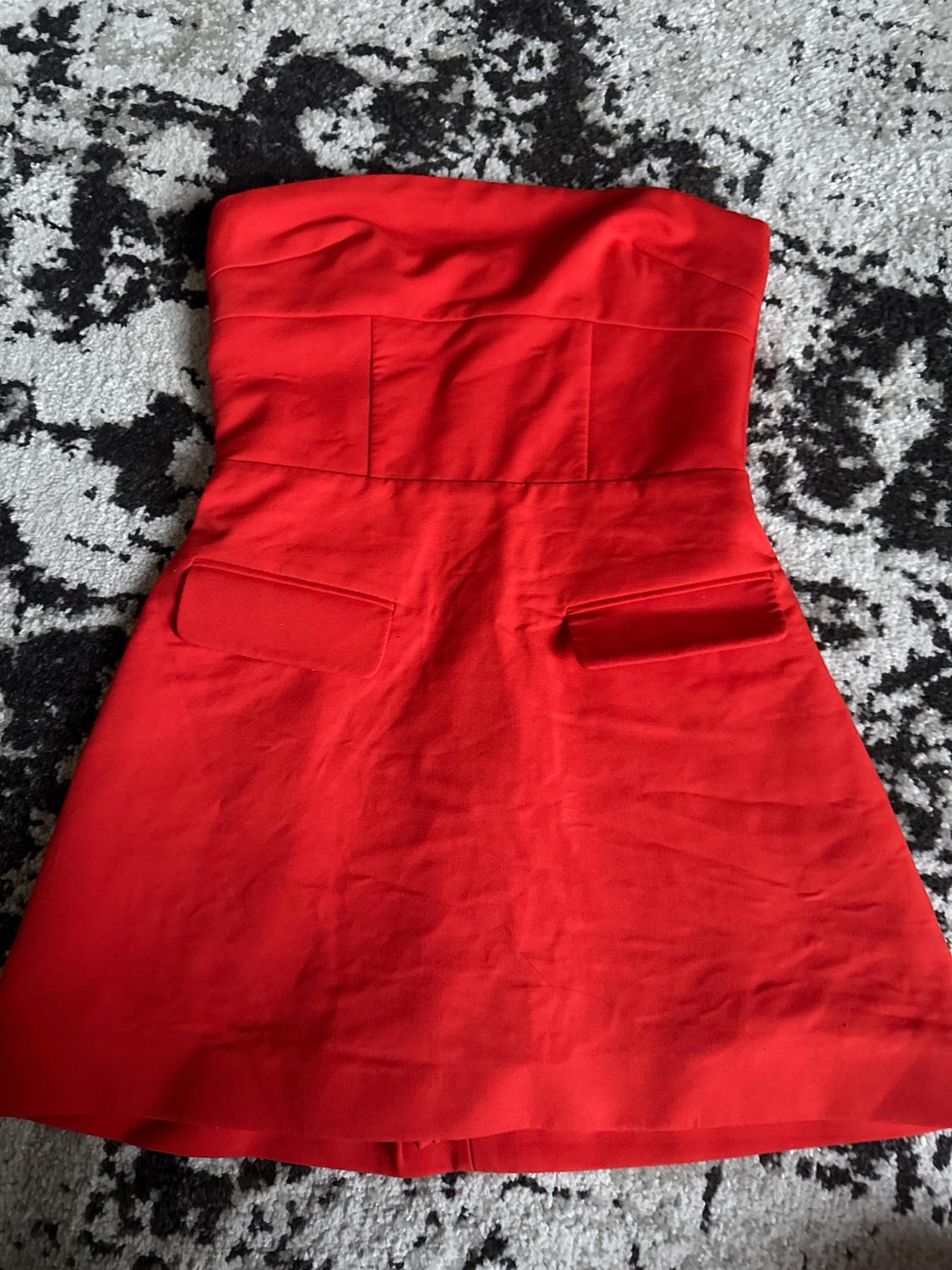 Strapless red dress on a black and white rug with an abstract design.