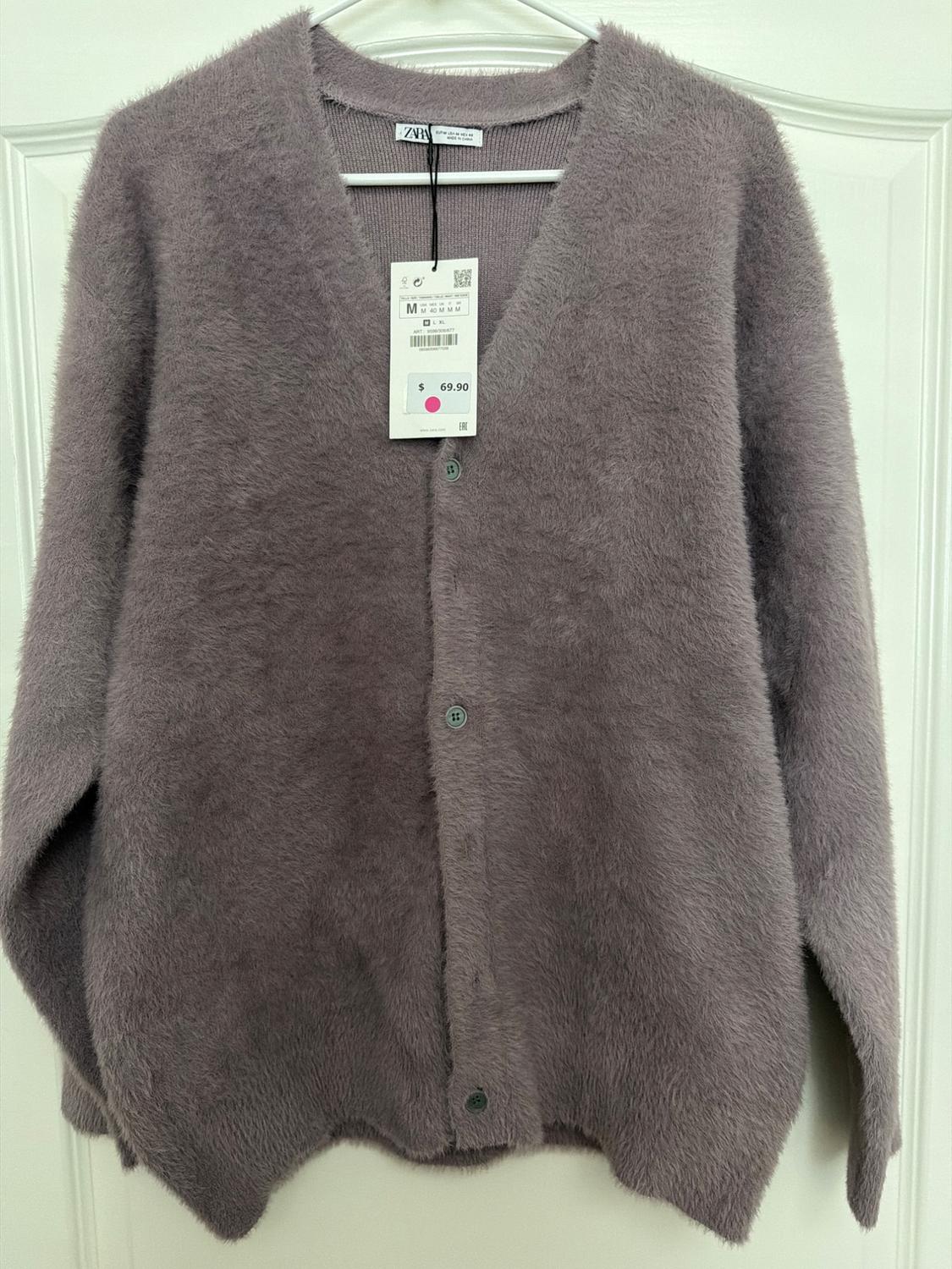 Soft lilac knit cardigan with buttons, hanging on a hanger. Visible tag with price of $69.90 and size M.