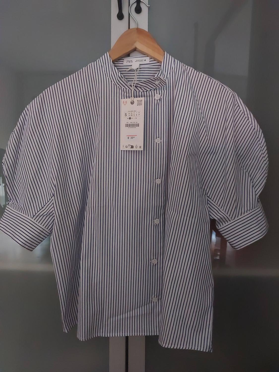 Short-sleeved vertical striped shirt with puffed sleeves, hanging on a hanger. Label with the text ZARA, S, € 35.95.
