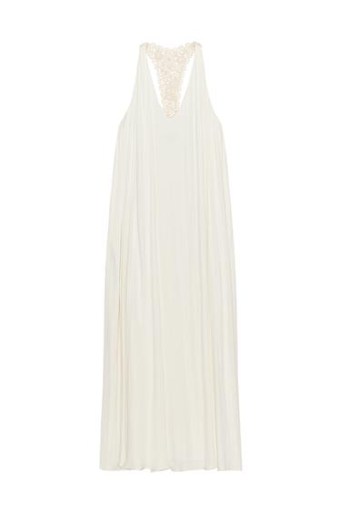 Back view of a long ecru dress with a V-neck and crochet knit detail on the back.