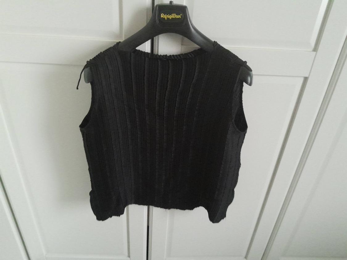 Black sleeveless ribbed textured top, hanging on a black hanger with the "RefrigWear" brand, against a white door background.