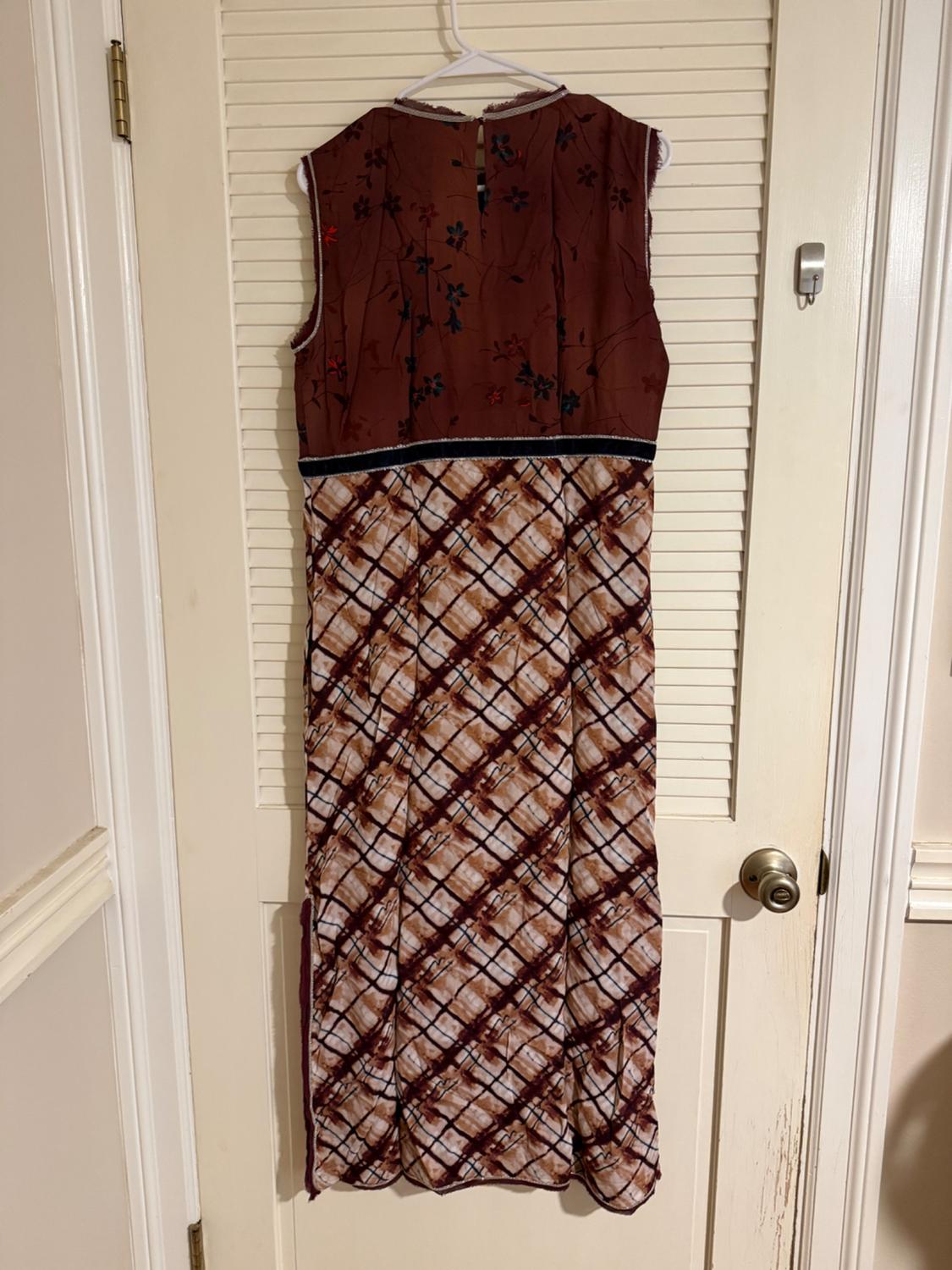 Sleeveless dress hanging on a door, with a brown, floral-print top and a skirt with a brown and white checkered design.