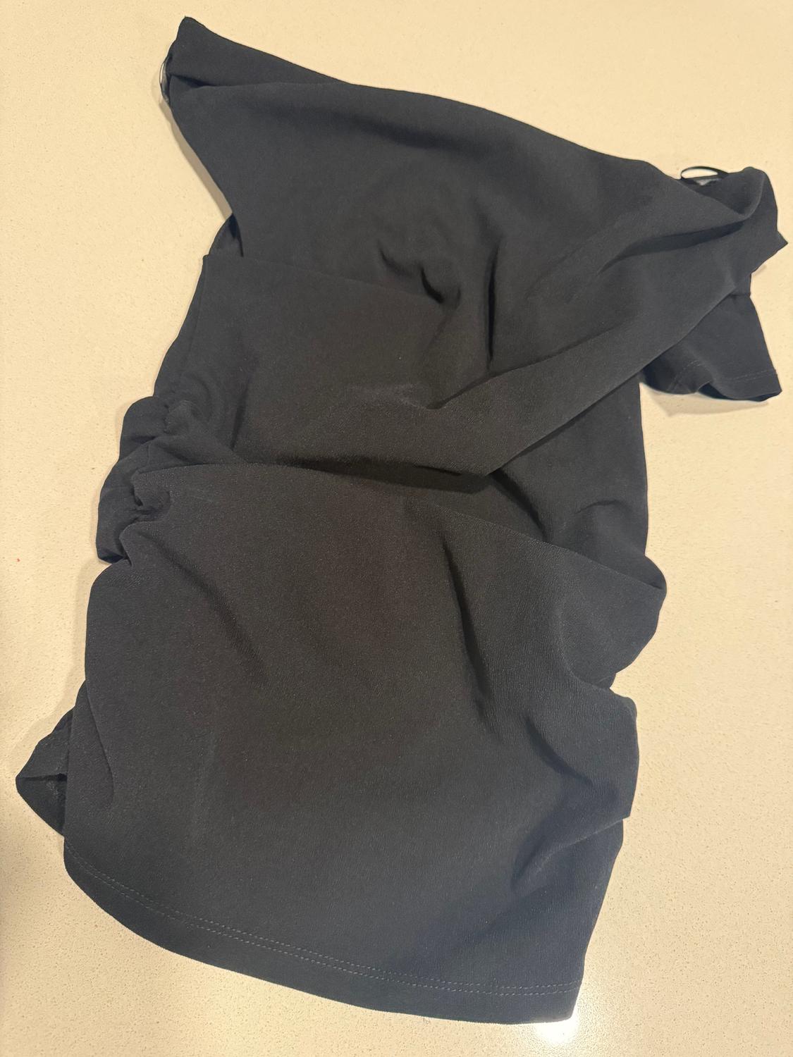 Crinkled black fabric on a beige surface, showing texture and drape of the material.