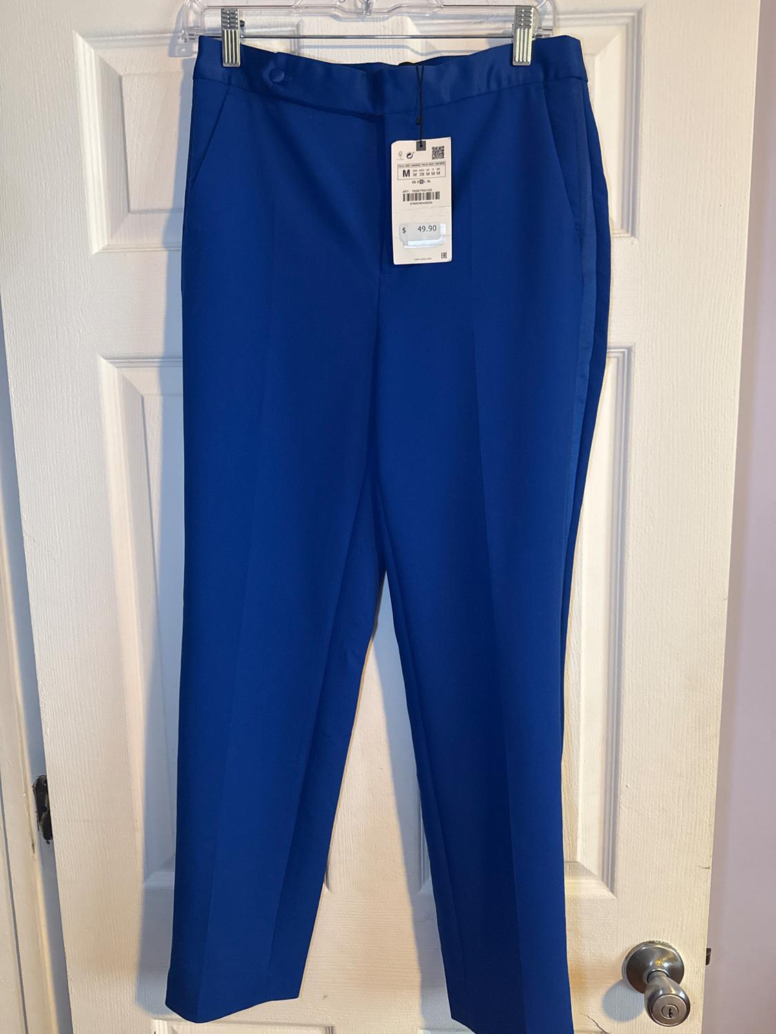 Blue trousers hanging on a white door with a price tag of 49.90.