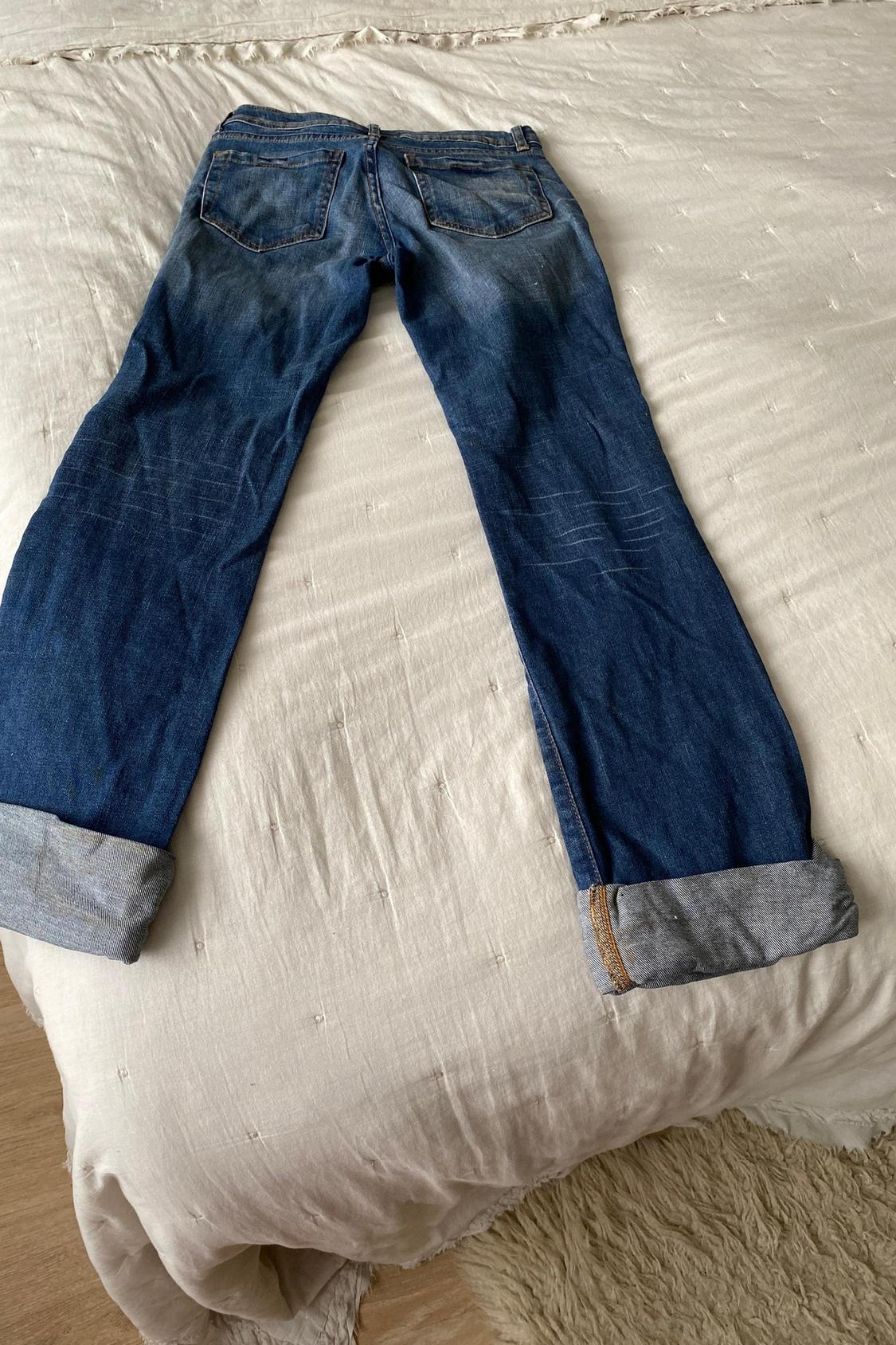 Rear view of blue jeans with back pockets and turned-up hem.