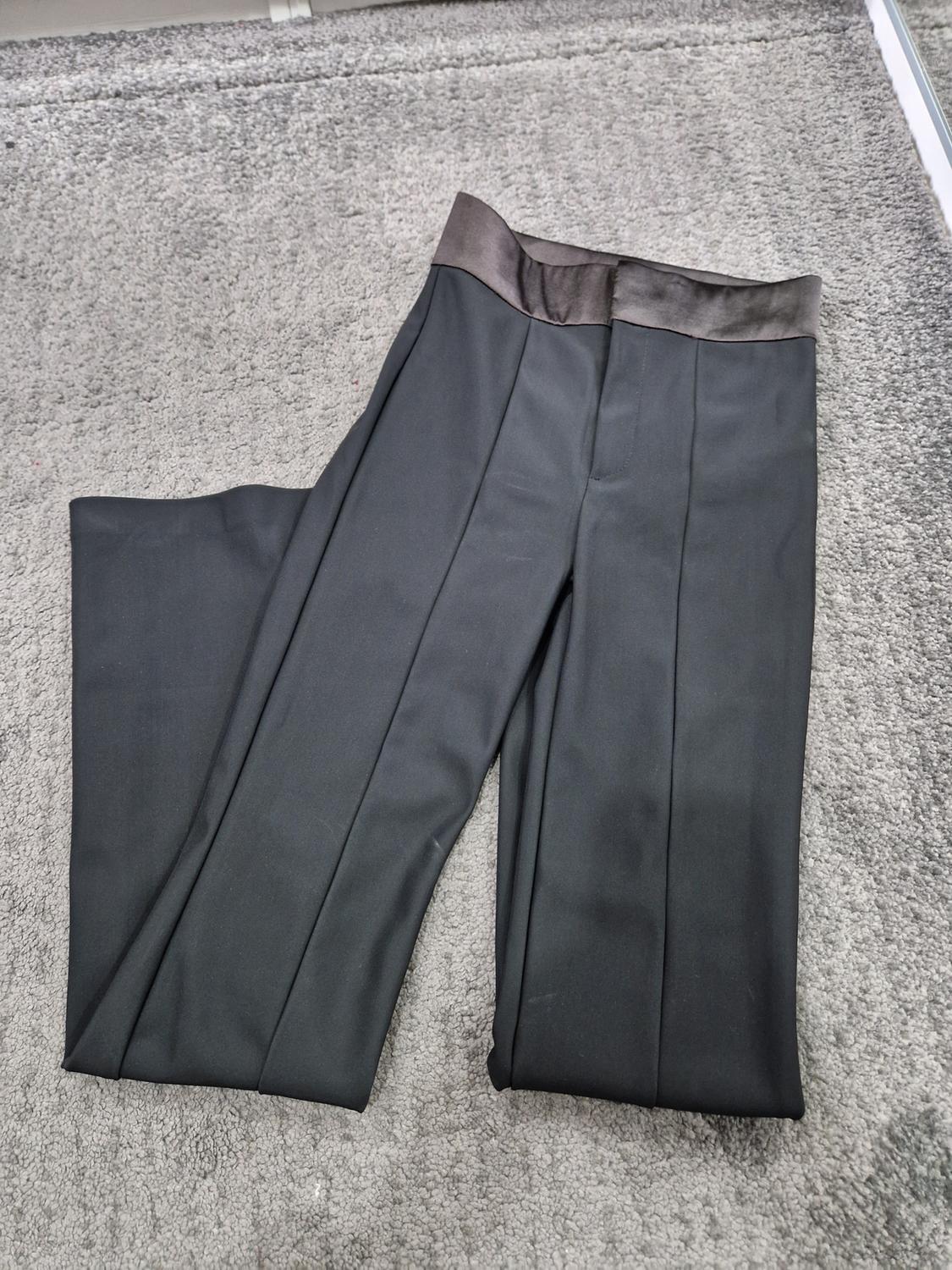 Black dress trousers with a satin waist, placed on a grey rug.