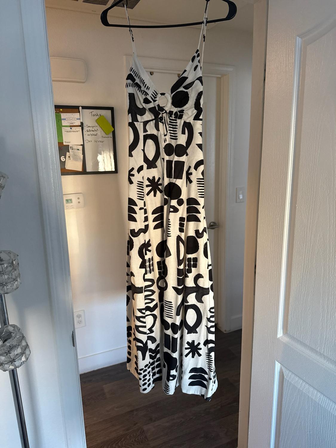 Long white dress with a black abstract pattern hanging on a door. In the background, a board with the text Tasks, Laundry, Nutribullet.