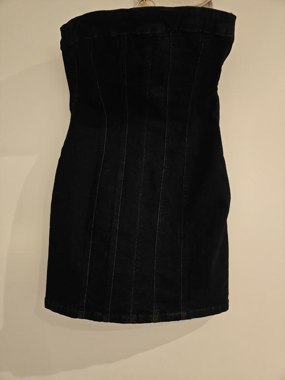 Strapless black dress, hanging, with visible vertical seams, on a white background.