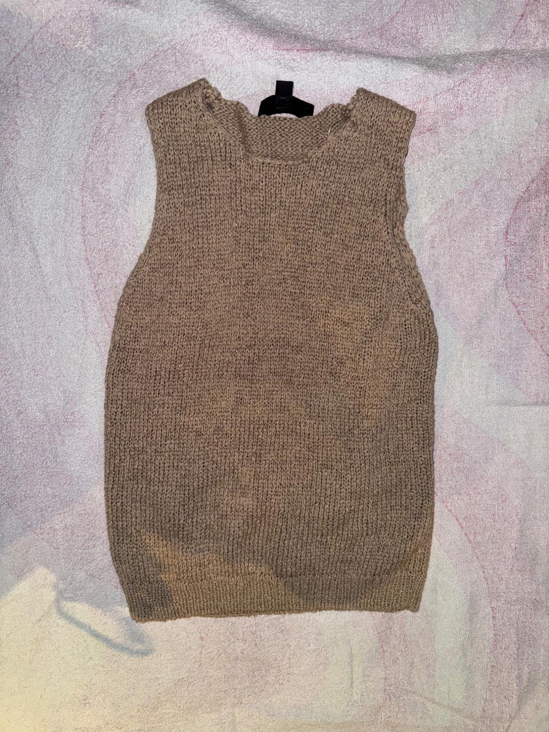 Brown sleeveless knitted vest on a textured surface in light tones.