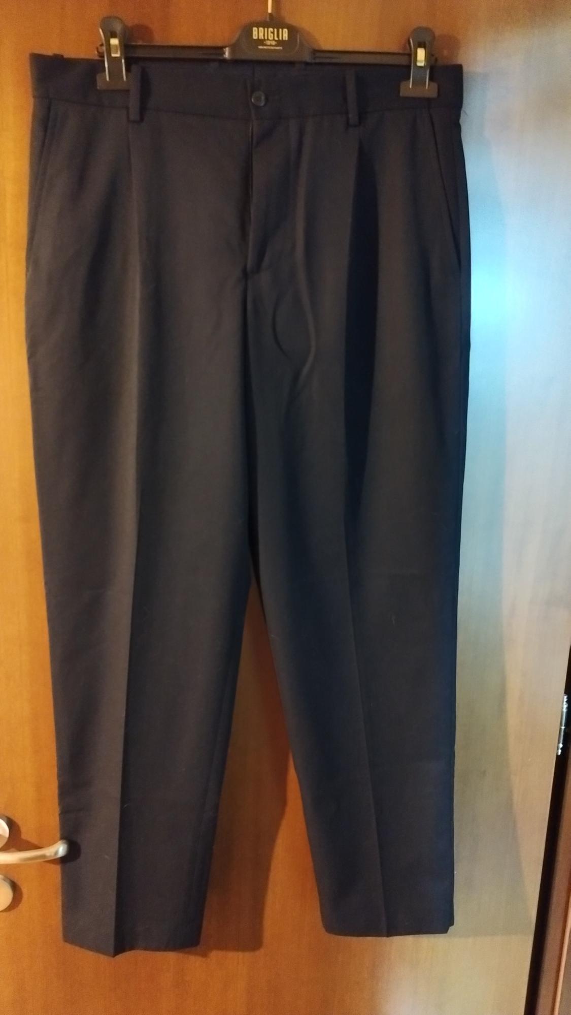 Dark trousers hanging on a hanger with the "BRIGLIA" brand visible, over a wooden door.