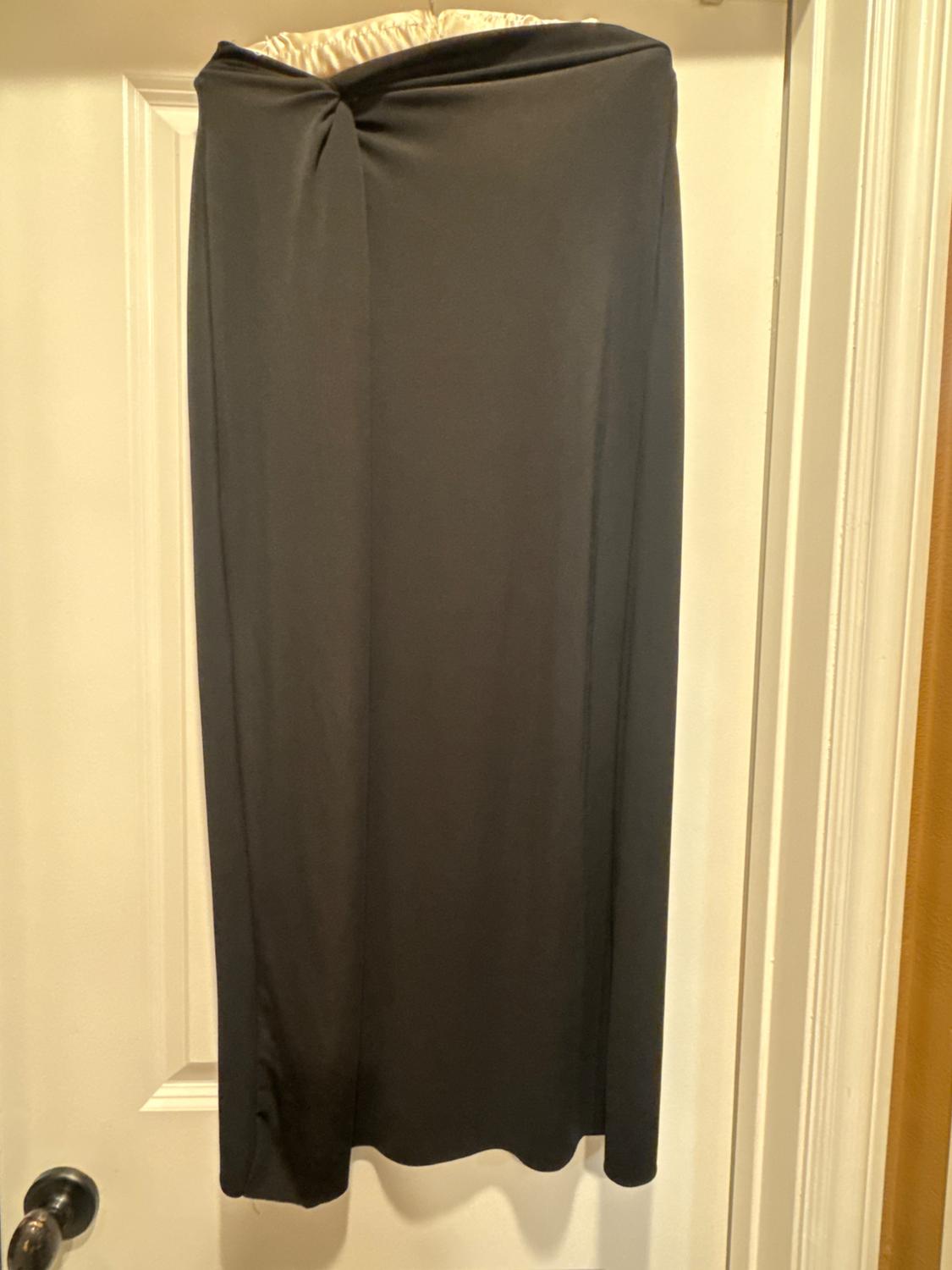 Long black skirt with a knot detail at the waist, hanging on a white door with a dark doorknob.