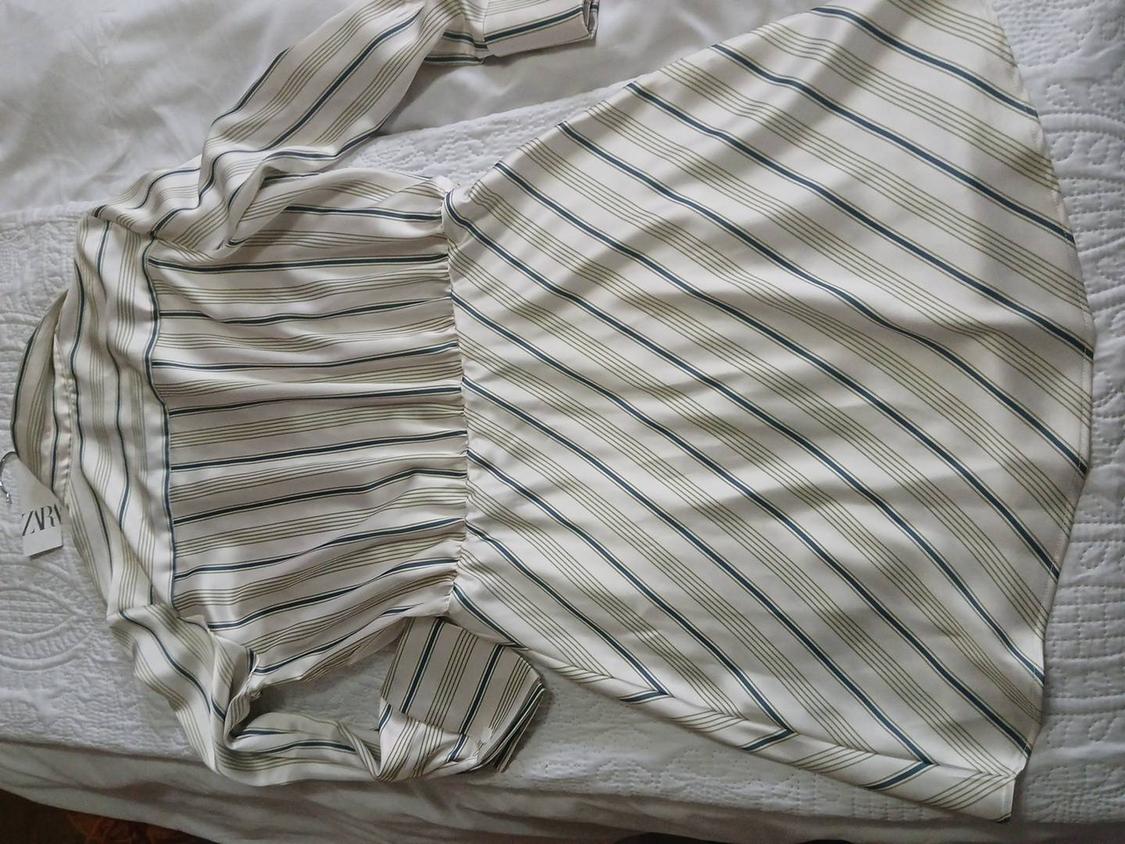 Black and white striped dress on a white bed. Visible label with text "ZARA".