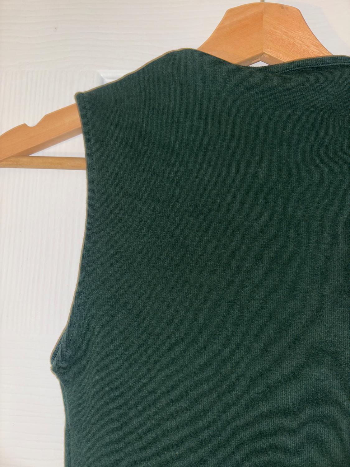 Dark green sleeveless waistcoat hanging on a wooden hanger against a textured white background.
