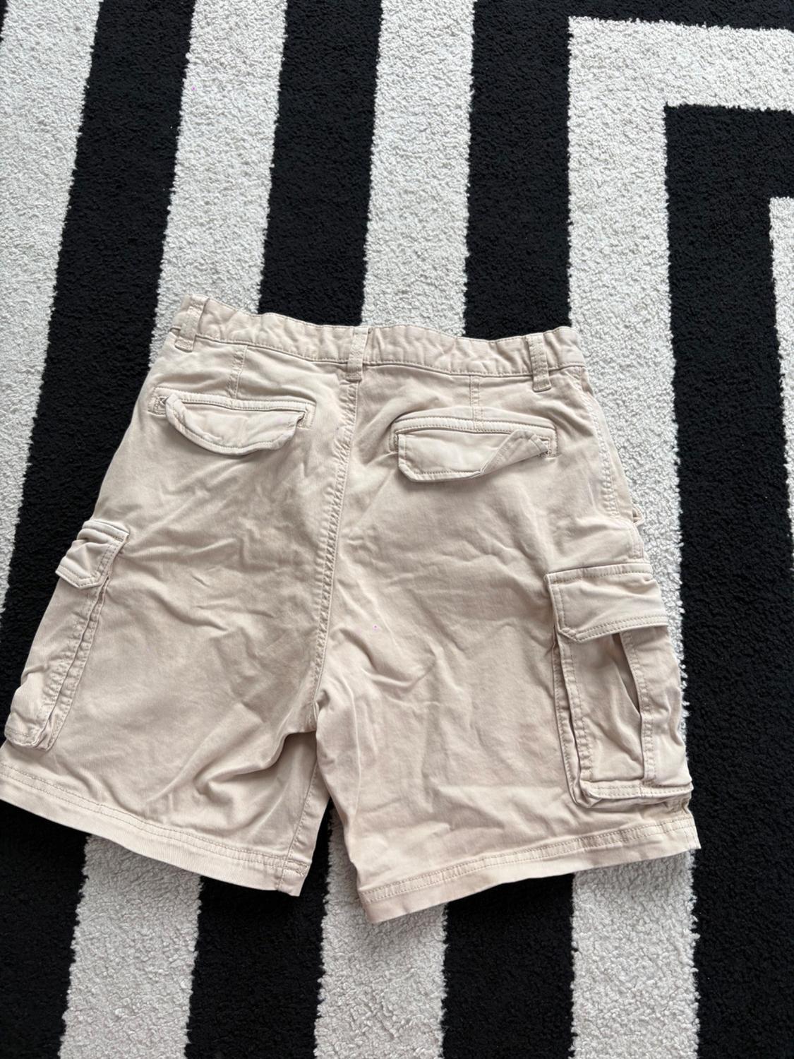 Elastic waistband shorts. Front pockets and back flap pockets. Flap patch pockets at legs. Front zip and button closure. - Image 2