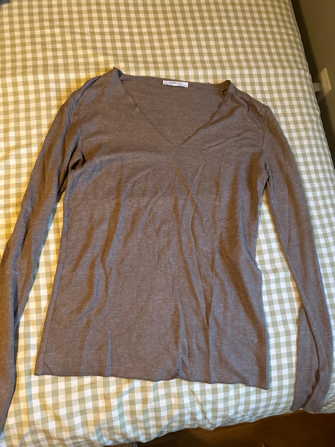 Brown long-sleeved V-neck jumper on a bed with a green and white checked bedspread. Visible label: Zara.