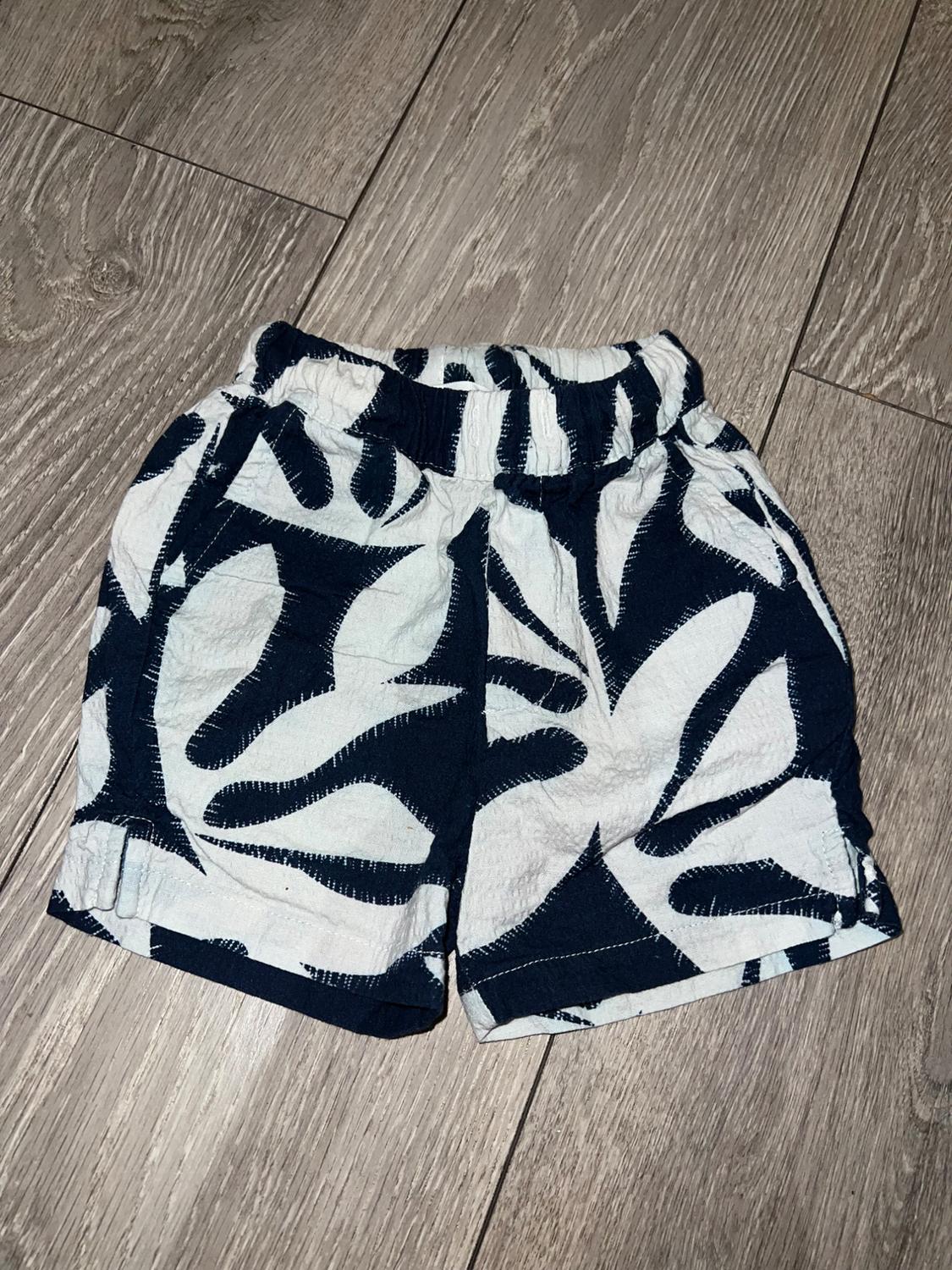 Black and white leaf print shorts on a light wooden floor.