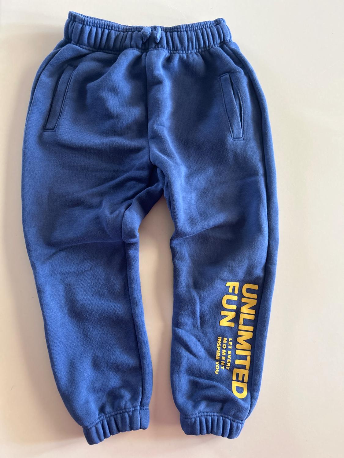 Blue joggers with pockets and yellow text on the right leg that reads "UNLIMITED FUN LET EVERY MOMENT INSPIRE YOU".