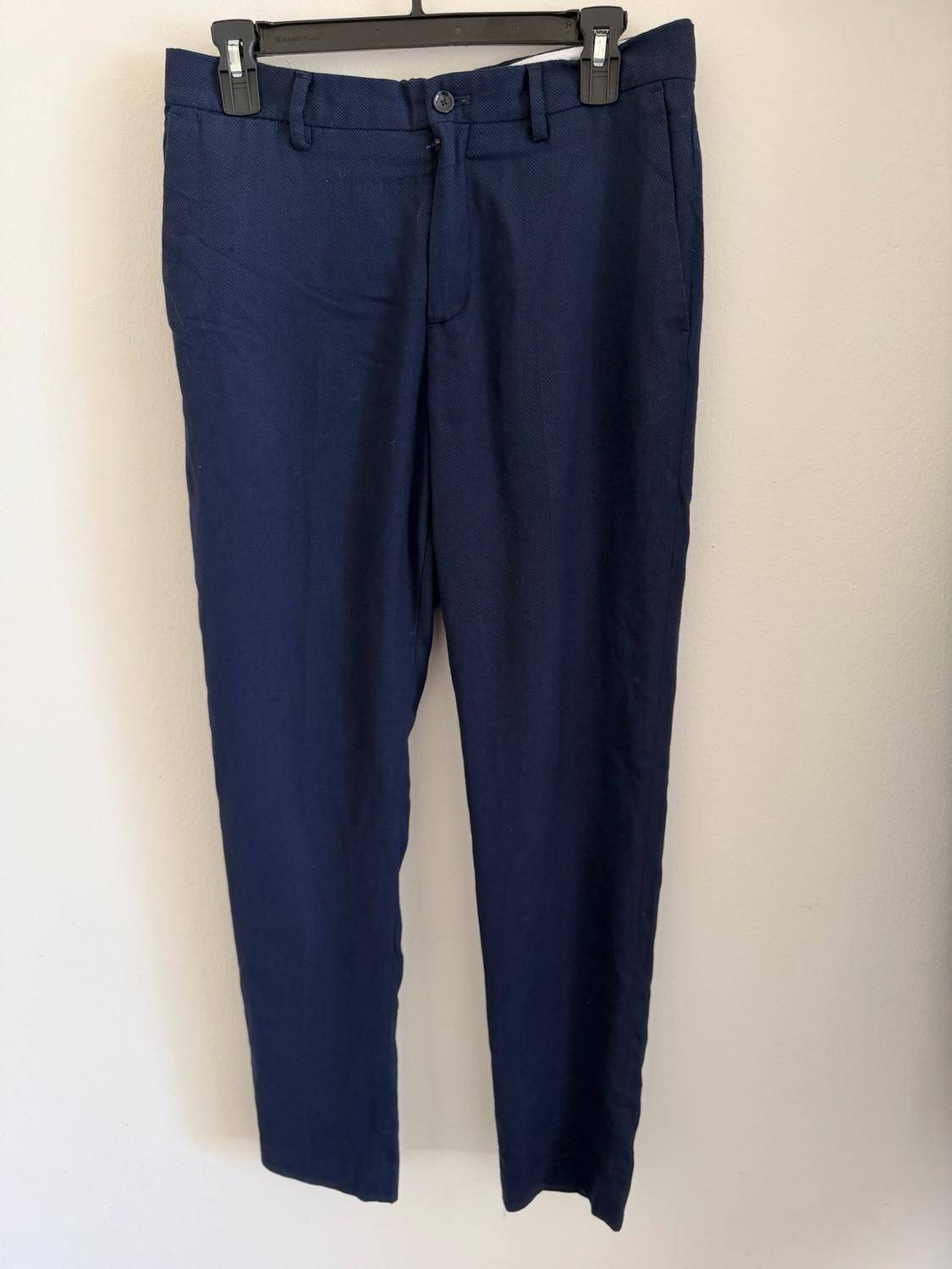 Navy dress pants hanging on a black hanger against a white background.