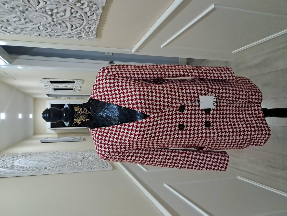 Mannequin in a red and white checked coat in a lit hallway, decorated with white carved wall panels.