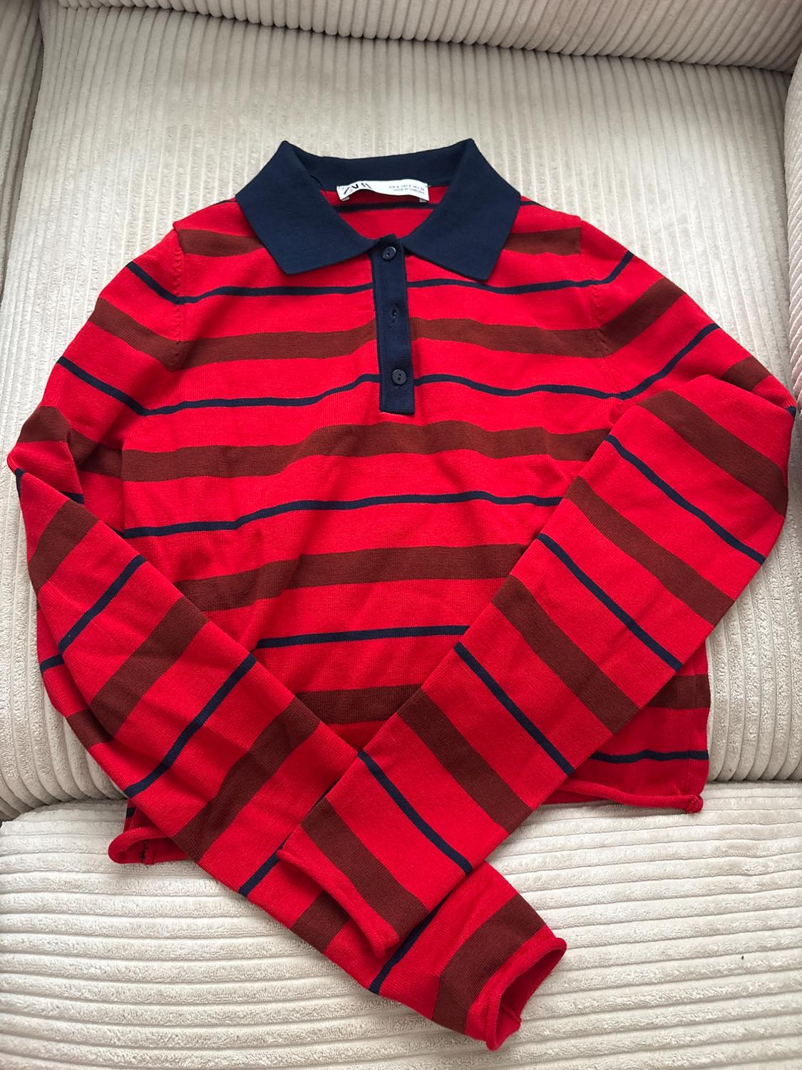 ZARA long-sleeved polo shirt with red, brown and blue stripes, a navy blue collar, on a light-coloured corduroy sofa.