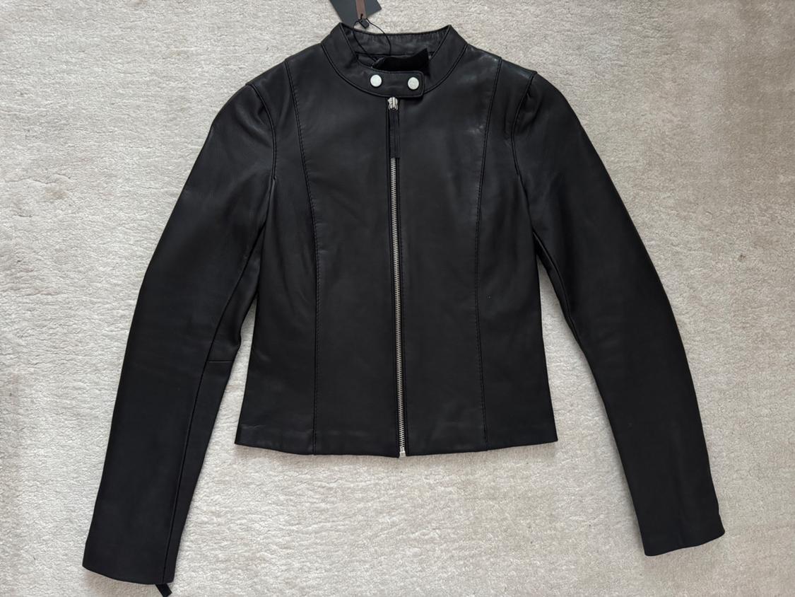 Black leather jacket with a front zip and high collar, on a light background. Elegant and modern design.