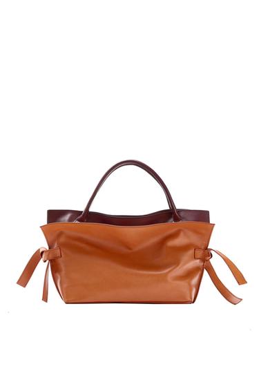 Handbag in camel and burgundy tones with short handles and knotted strap details on the sides, photographed against a white background.
