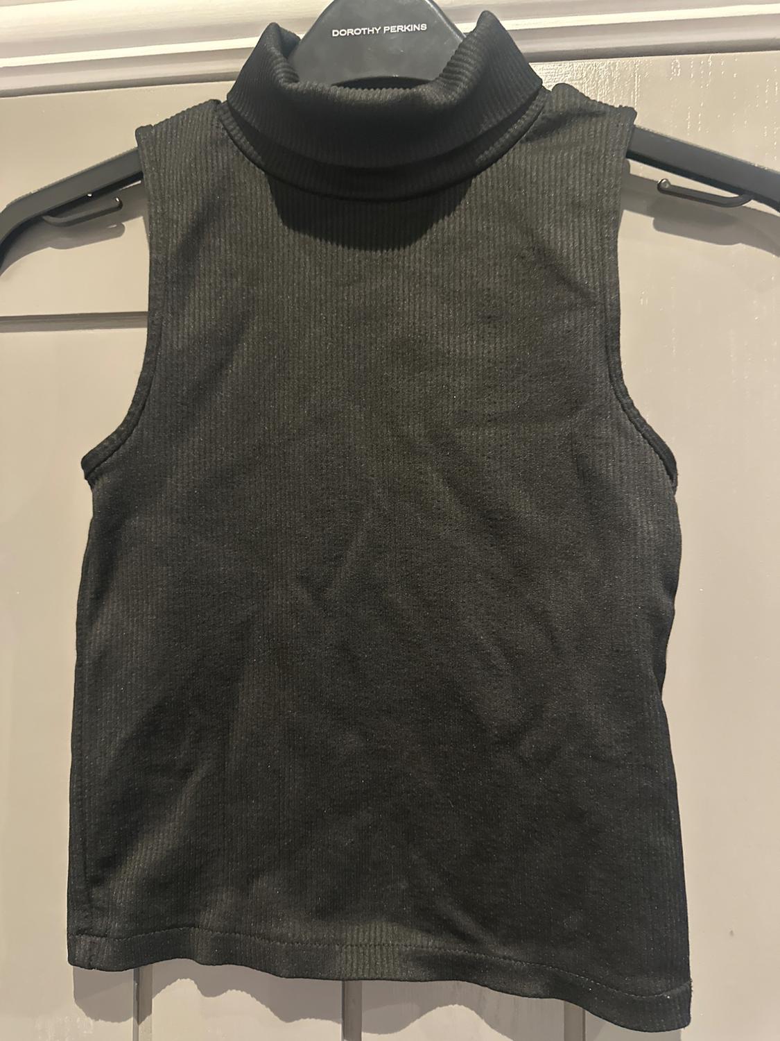 Black high neck sleeveless top, hanging on a black hanger that says "Dorothy Perkins", against a light background.