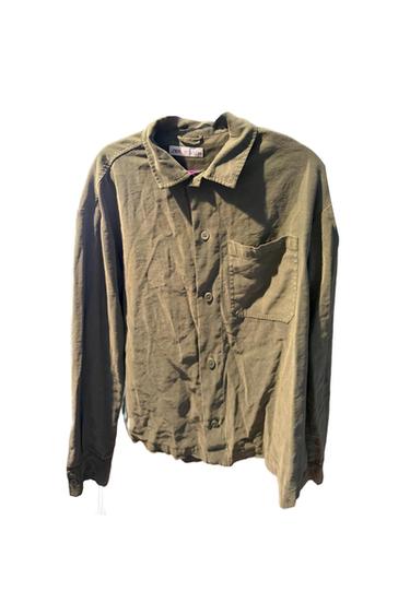 Olive green long-sleeved collared shirt, with button fastening and chest pocket on a white background. Interior tag with text zara.