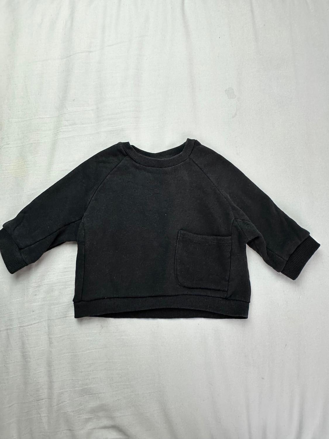 Black long-sleeve hoodie for boys with a crew neck, ribbed cuffs and hem, and a patch pocket on the chest, on a white background.