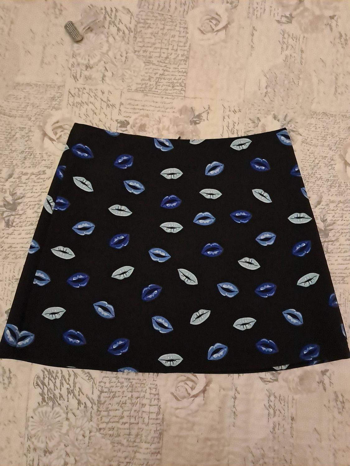 Black skirt with a print of blue and sky-blue lips, placed against a light background with handwritten lettering.