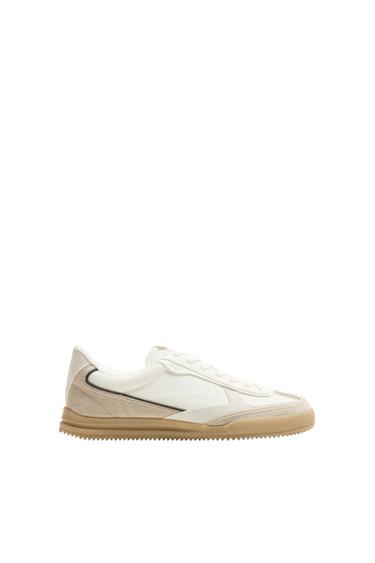 Side view of a white trainer with a beige sole.