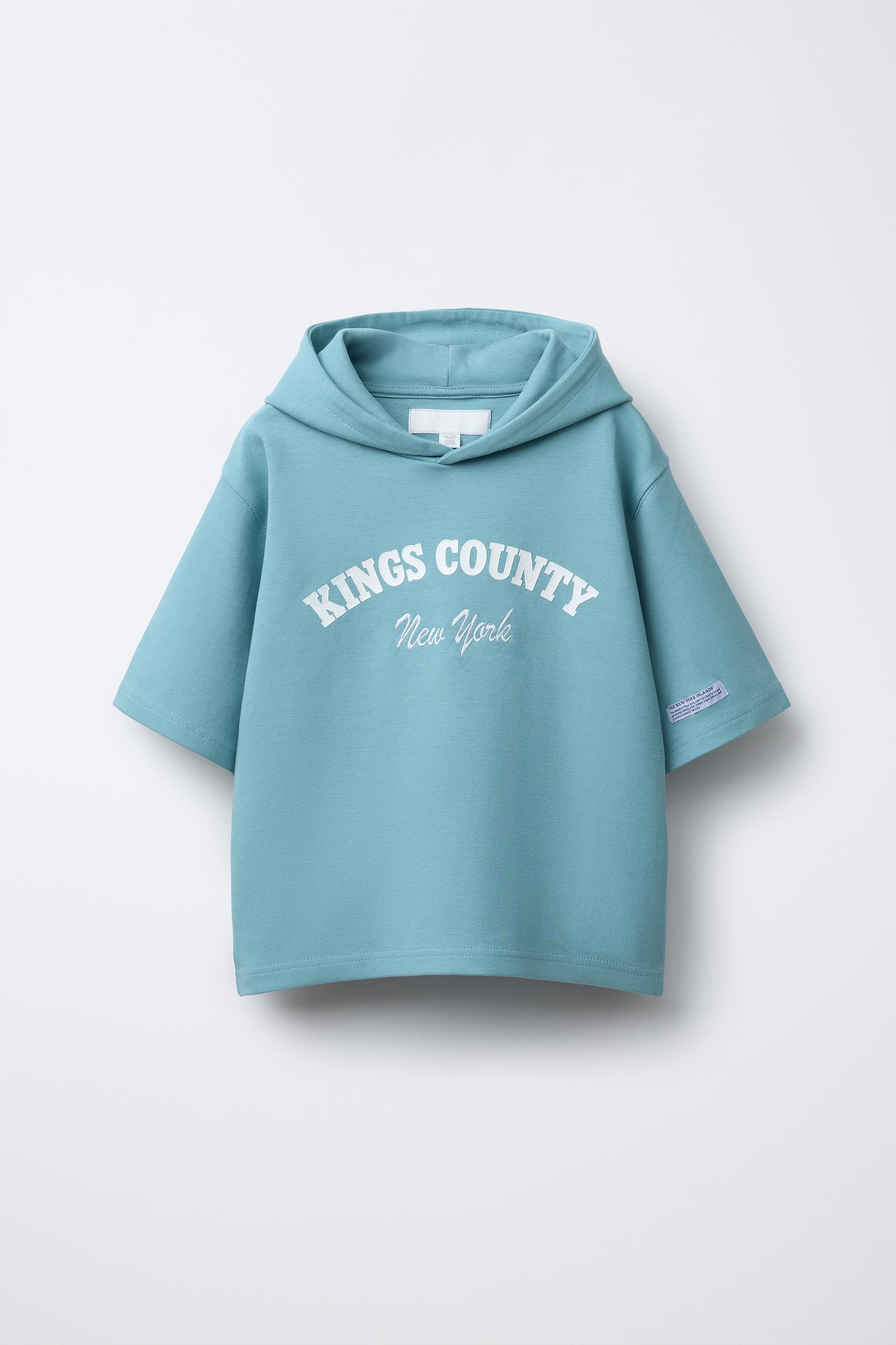 SWEAT À MANCHES COURTES, CAPUCHE ET INSCRIPTION