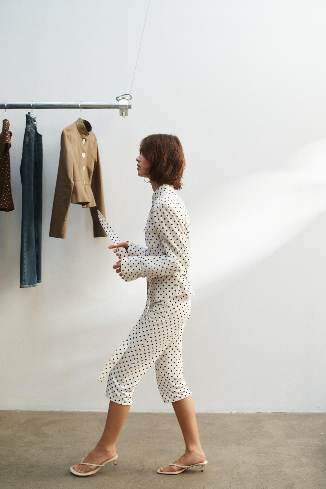 Conjunto de blusa y pantalón blanco con lunares negros, blusa de manga larga y pantalón capri, sandalias beige.