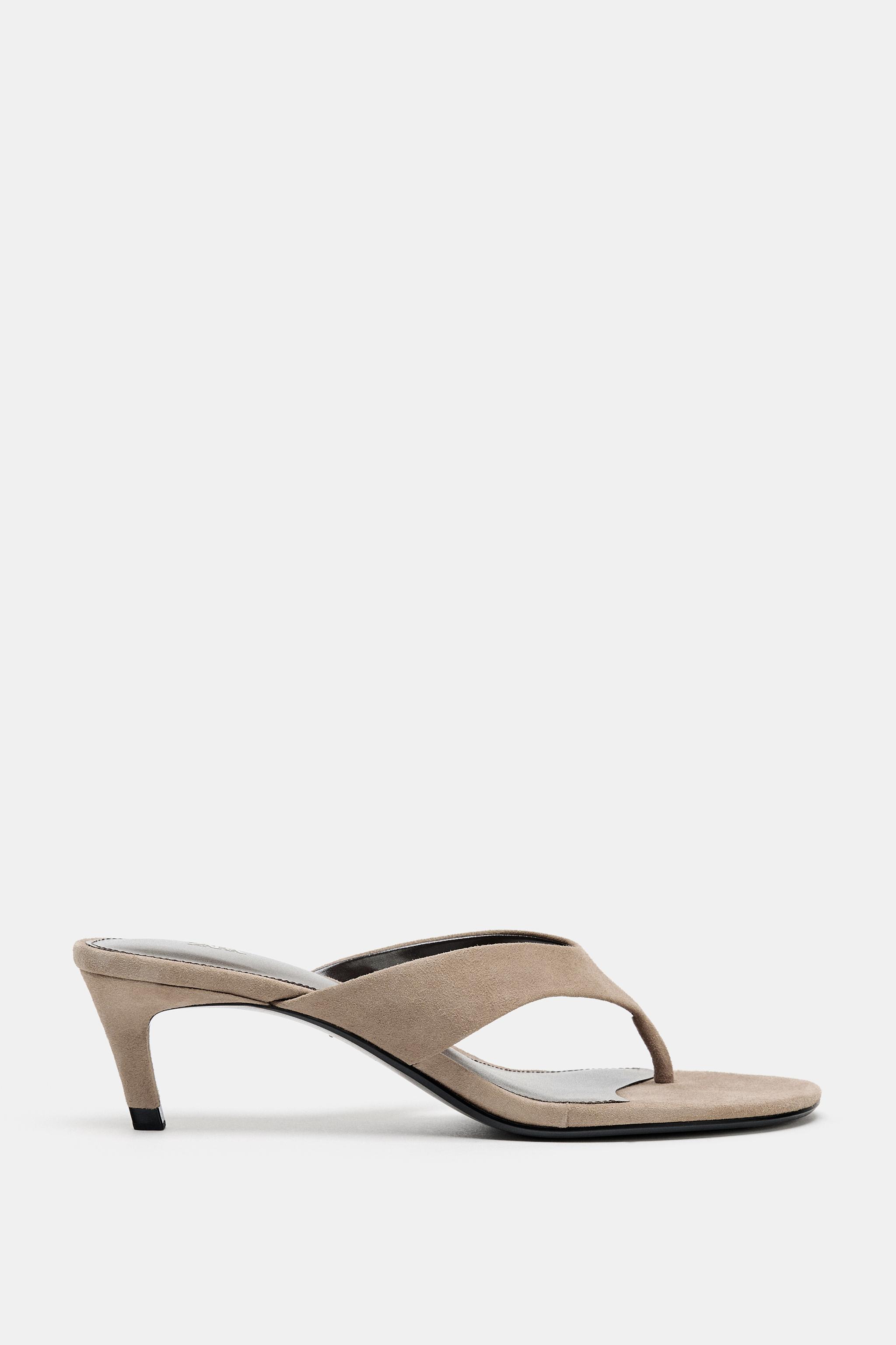 Side view of a beige sandal with a low heel and a V-shaped strap design.