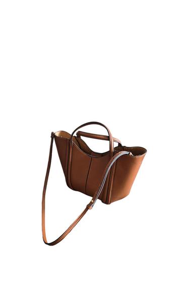Minimalist brown handbag with vertical stitching, two short handles, and a long adjustable strap, on a white background.