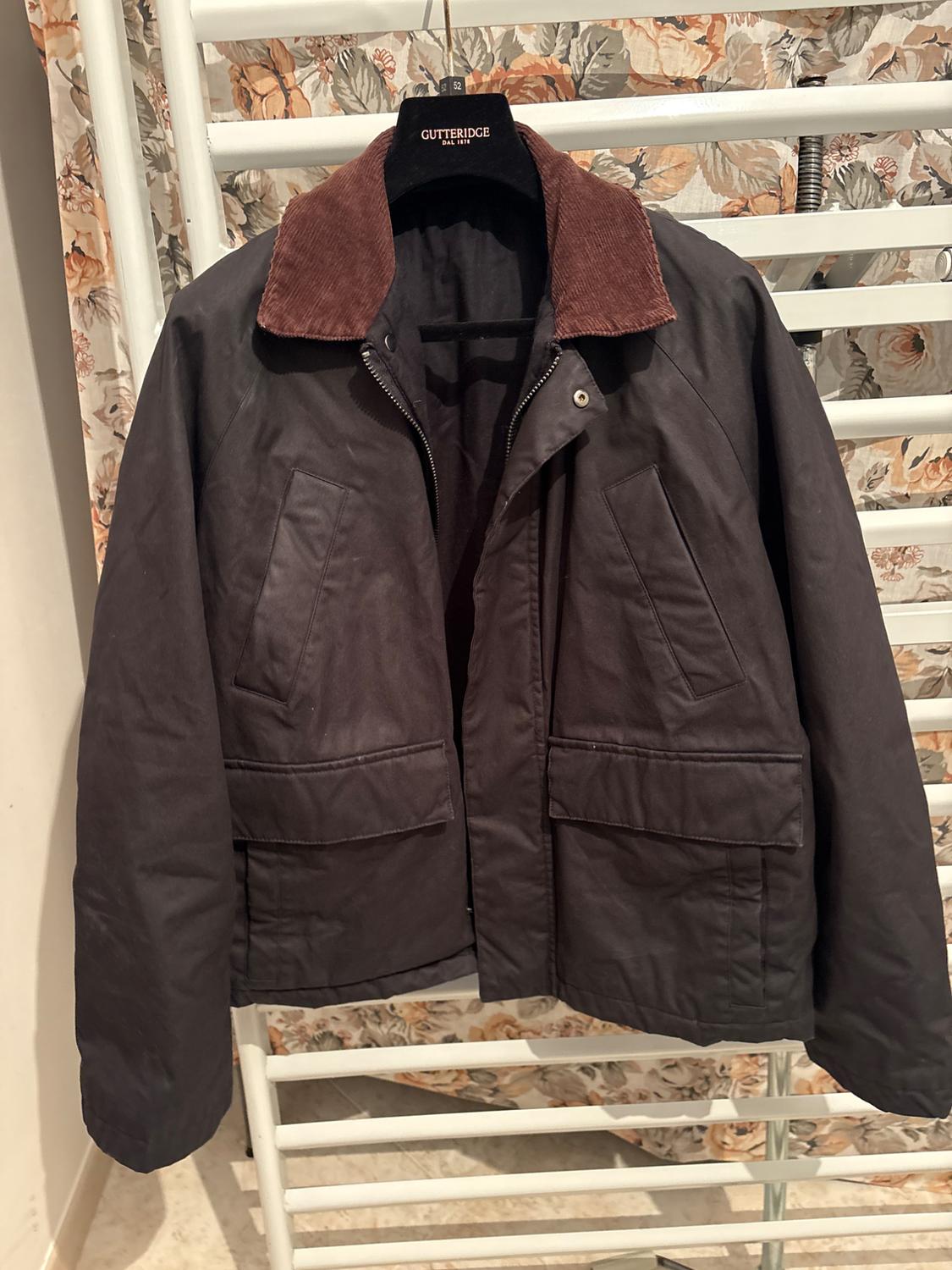 Dark brown jacket with a brown corduroy collar, hanging on a Gutteridge hanger, floral fabric background.