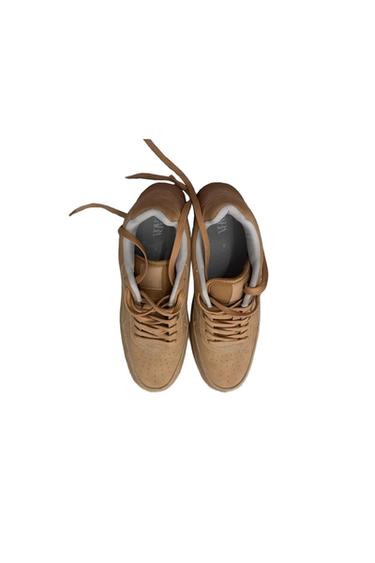 A pair of light brown sneakers seen from above, with laces and a gray inner lining. The "ZARA" can be read on the template.